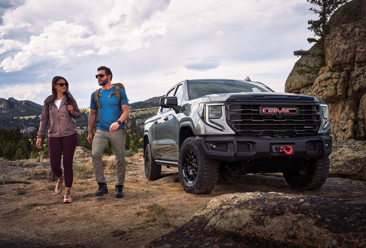 Two people walking beside a GMC Truck