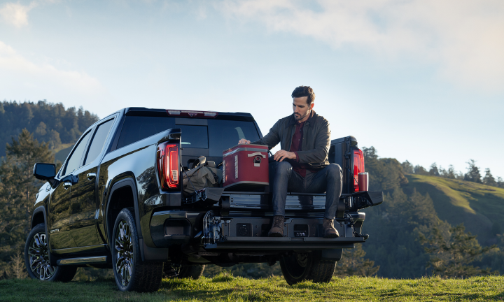 Man eating lunch on tailgate of GM truck